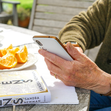 Person using a smartphone at a table outdoors