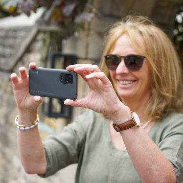 Woman using a Doro smartphone to take photos outdoors, easy-to-use camera features