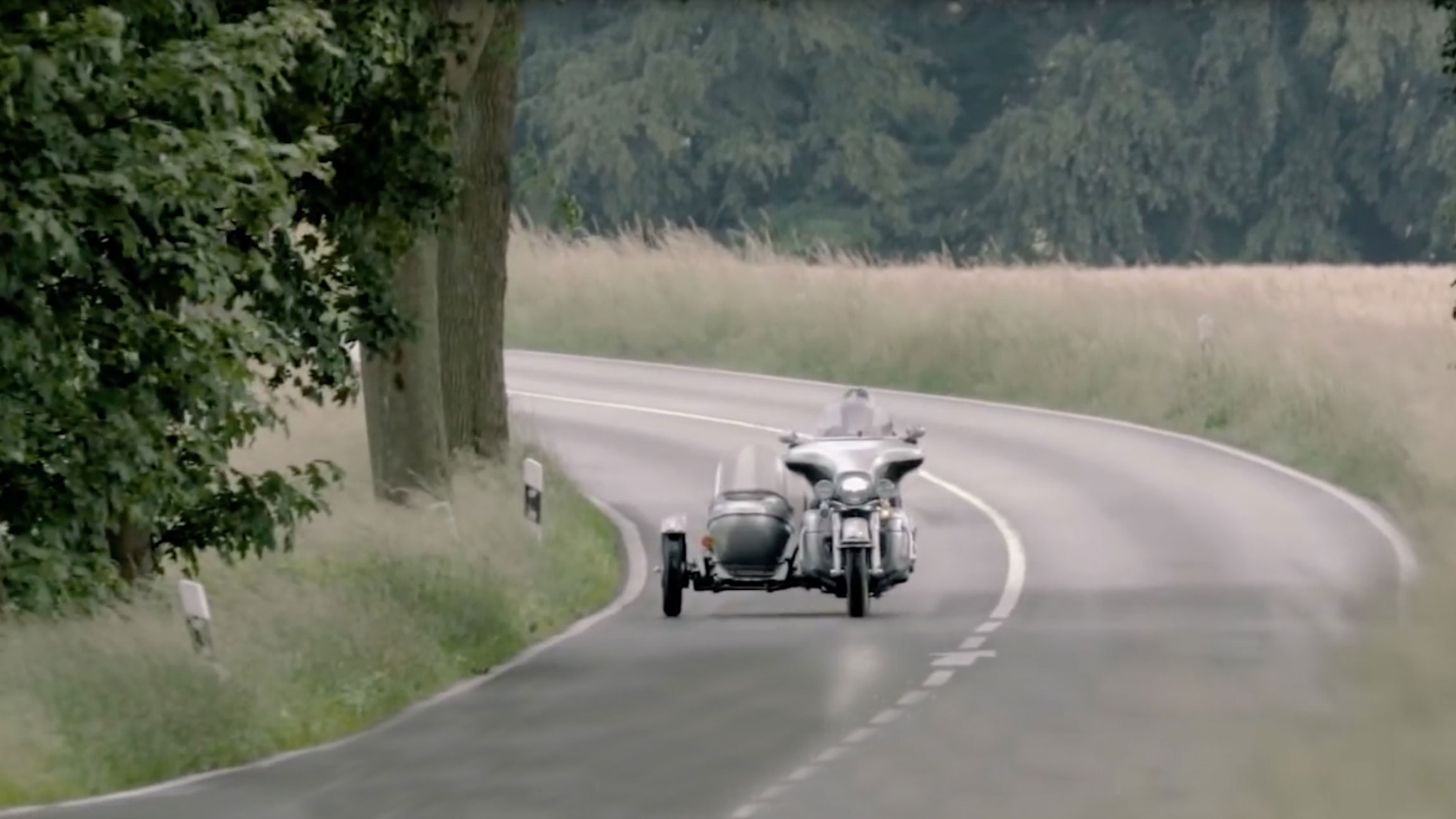 Man riding a motorcycle with sidecar on a countryside road