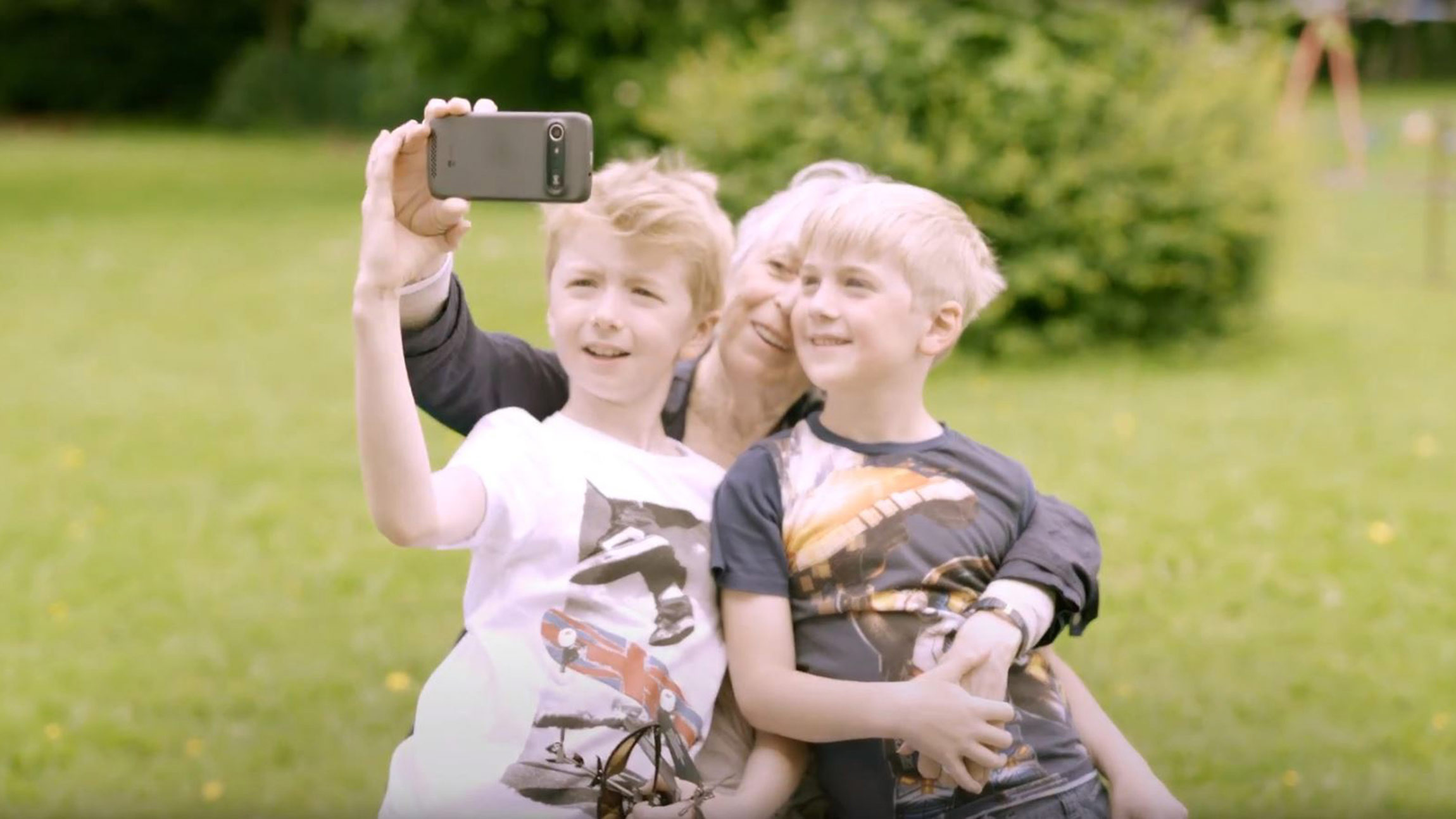 Grandmother taking selfie with two children outdoors