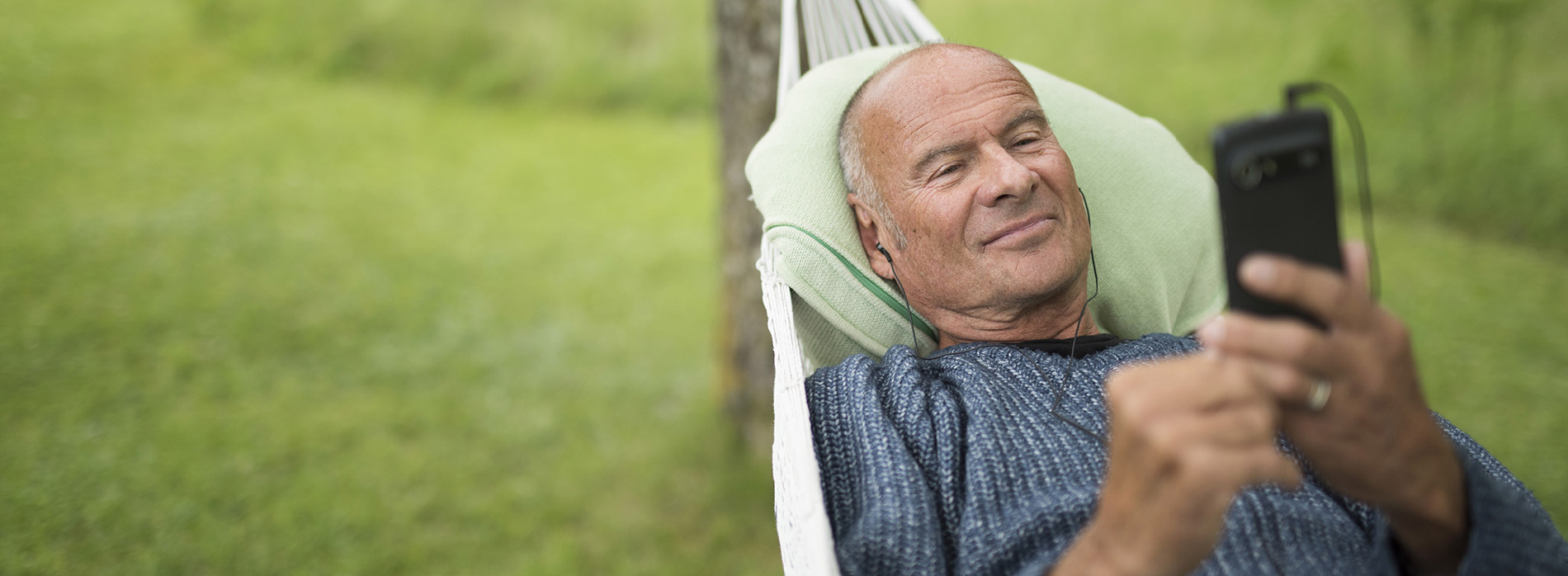 Man relaxing outdoors while listening to Spotify on a Doro smartphone