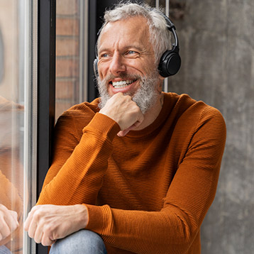 Man wearing headphones smiling while listening to audio