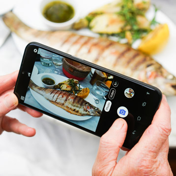 Person using a Doro smartphone camera to take a photo of food at a restaurant