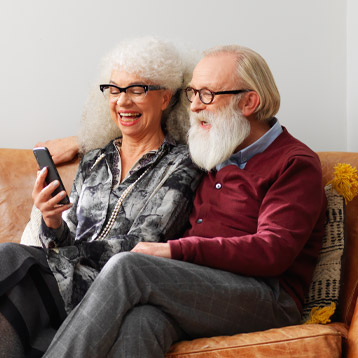 Older couple using a Doro smartphone together on a sofa