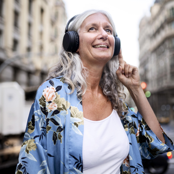 Kvinna lyssnar på musik med Doro-telefon och hörlurar.