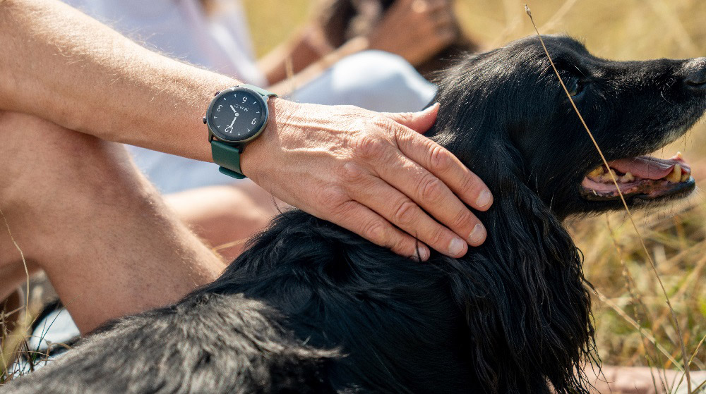 Person wearing a smartwatch while petting a dog outdoors