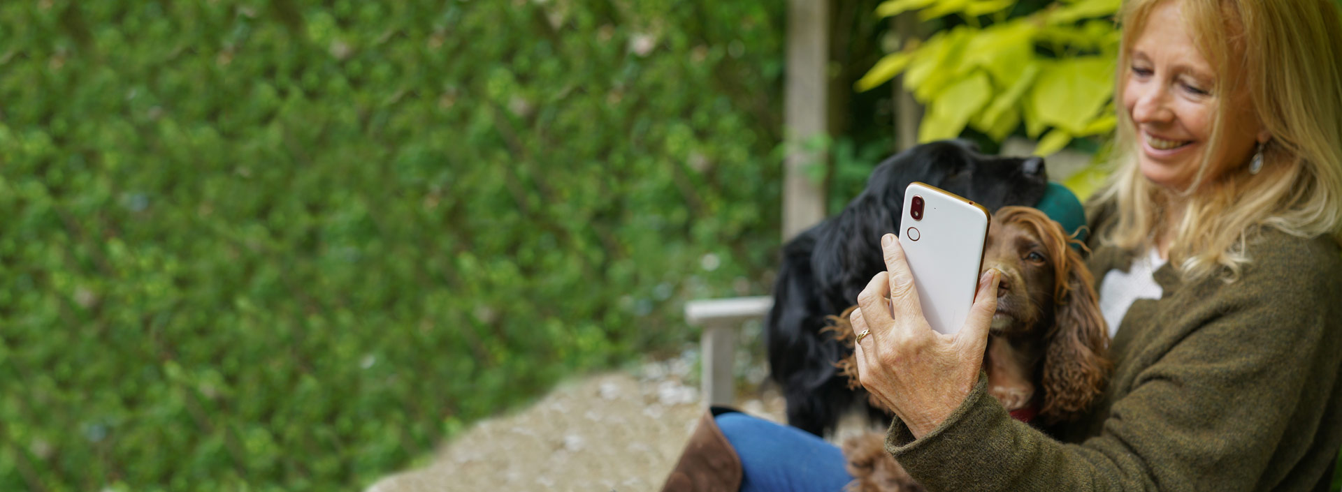 Woman making a video call on a Doro smartphone while sitting outdoors with her dogs