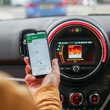 Senior using Doro smartphone for GPS navigation while driving with Google Maps directions