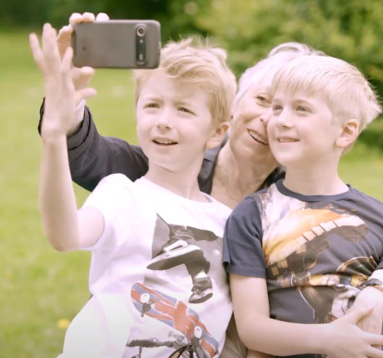 Woman snapping selfie with her grandchildren.