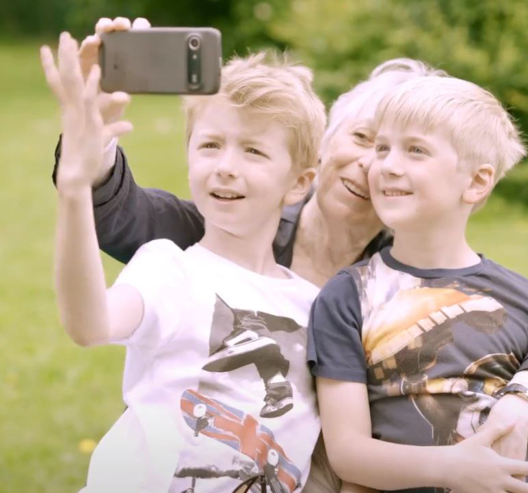 Nainen ottamassa selfietä lastenlastensa kanssa.