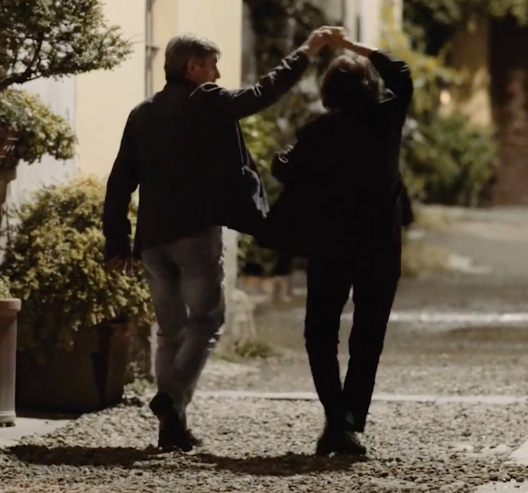 Couple dancing on gravel path.