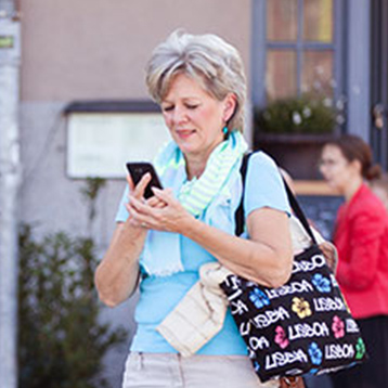 Woman using a Doro smartphone on city street.