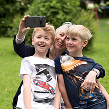 Kvinna använder Doro-telefon för att ta selfie tillsammans med barnbarnen.