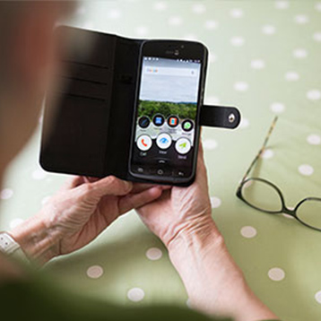 Woman holding a Doro smartphone with a cover.