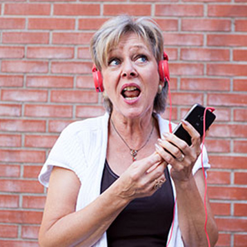 Woman listening to music with a Doro smartphone and headphones.