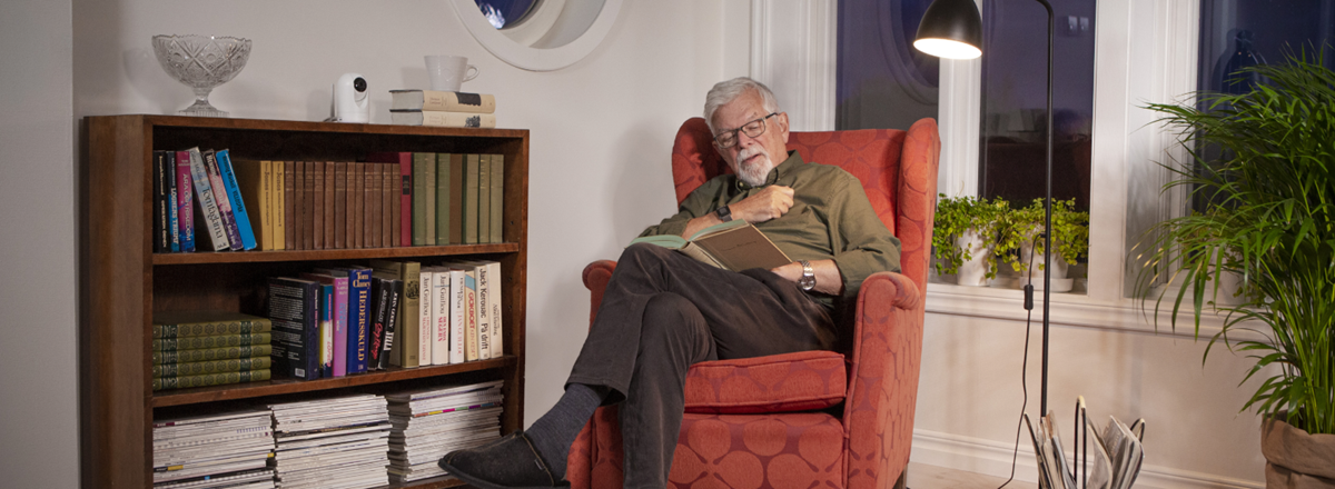 senior sitting in an armchair reading a book 